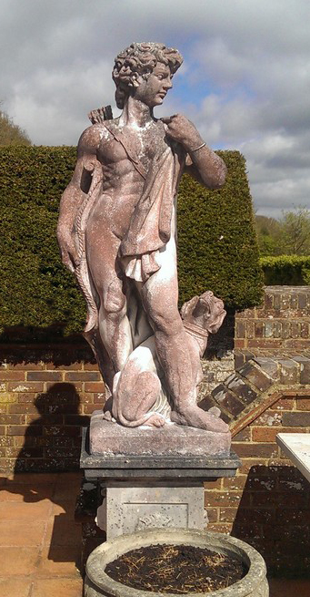 A pair of reconstituted stone garden statues modelled as a classical hunter and a maiden height overall 7ft 7in.